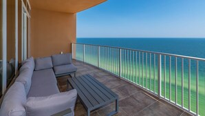 Ein Balkon mit einer Couch und einem Tisch, mit Blick auf das klare, blaue Meer.