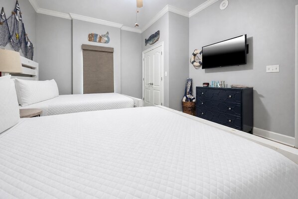 Habitación de hotel con dos camas, televisión, cómoda y decoración náutica.