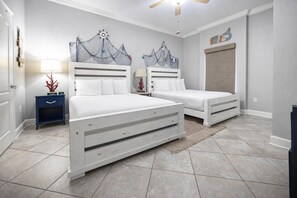 Une chambre avec deux lits, une table de chevet, une lampe et un ventilateur de plafond.