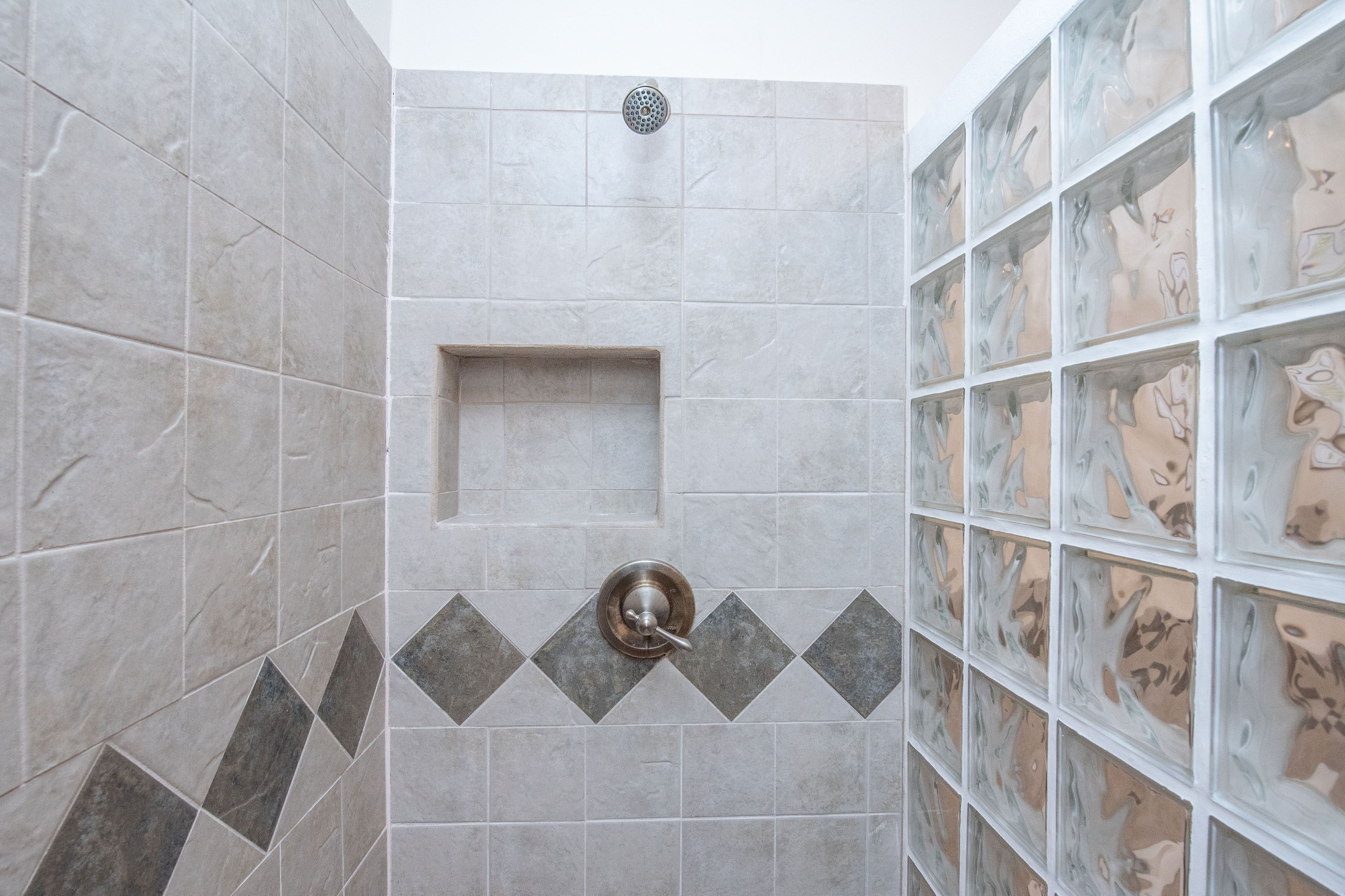 Un baño con baldosas grises, zona de ducha y pared decorativa con diseños abstractos.
