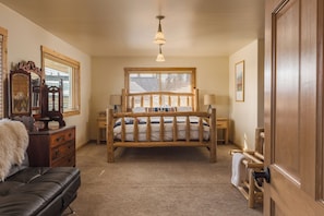 A bedroom with a wooden bed, a dresser, a mirror, and a window with blinds. - Majestic Valley Wilderness Lodge (Sutton)