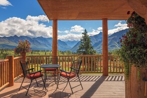 A wooden deck with a table and chairs, overlooking a mountainous landscape. - Majestic Valley Wilderness Lodge (Sutton)