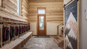 A log cabin interior with a row of lockers, a wooden staircase, and a stone floor. - Majestic Valley Wilderness Lodge (Sutton)
