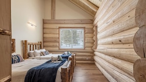 A log cabin bedroom with a large window, wooden walls, and a wooden floor. - Majestic Valley Wilderness Lodge (Sutton)
