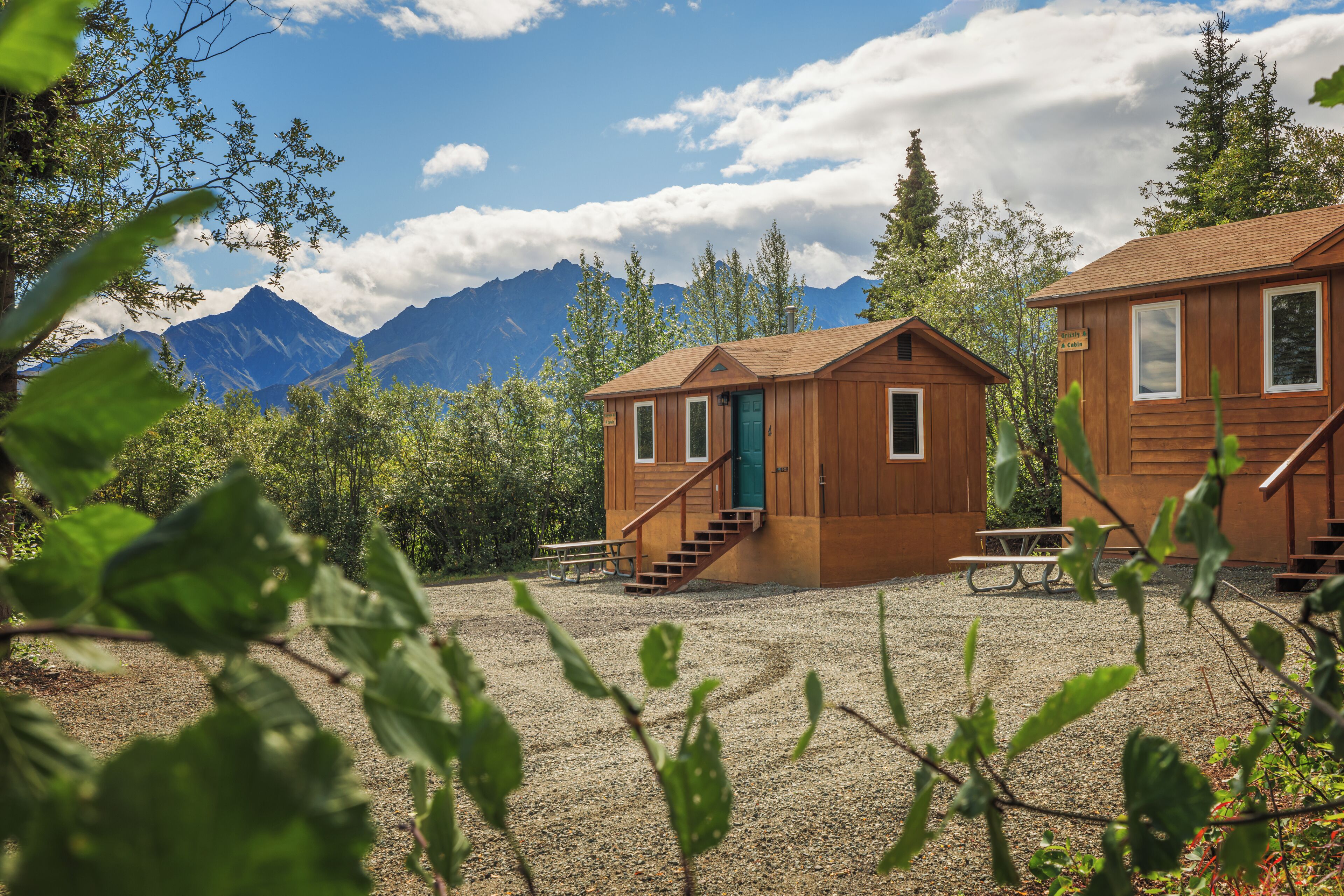 A cabin with a wooden exterior, a green door, and a staircase leading to the entrance.