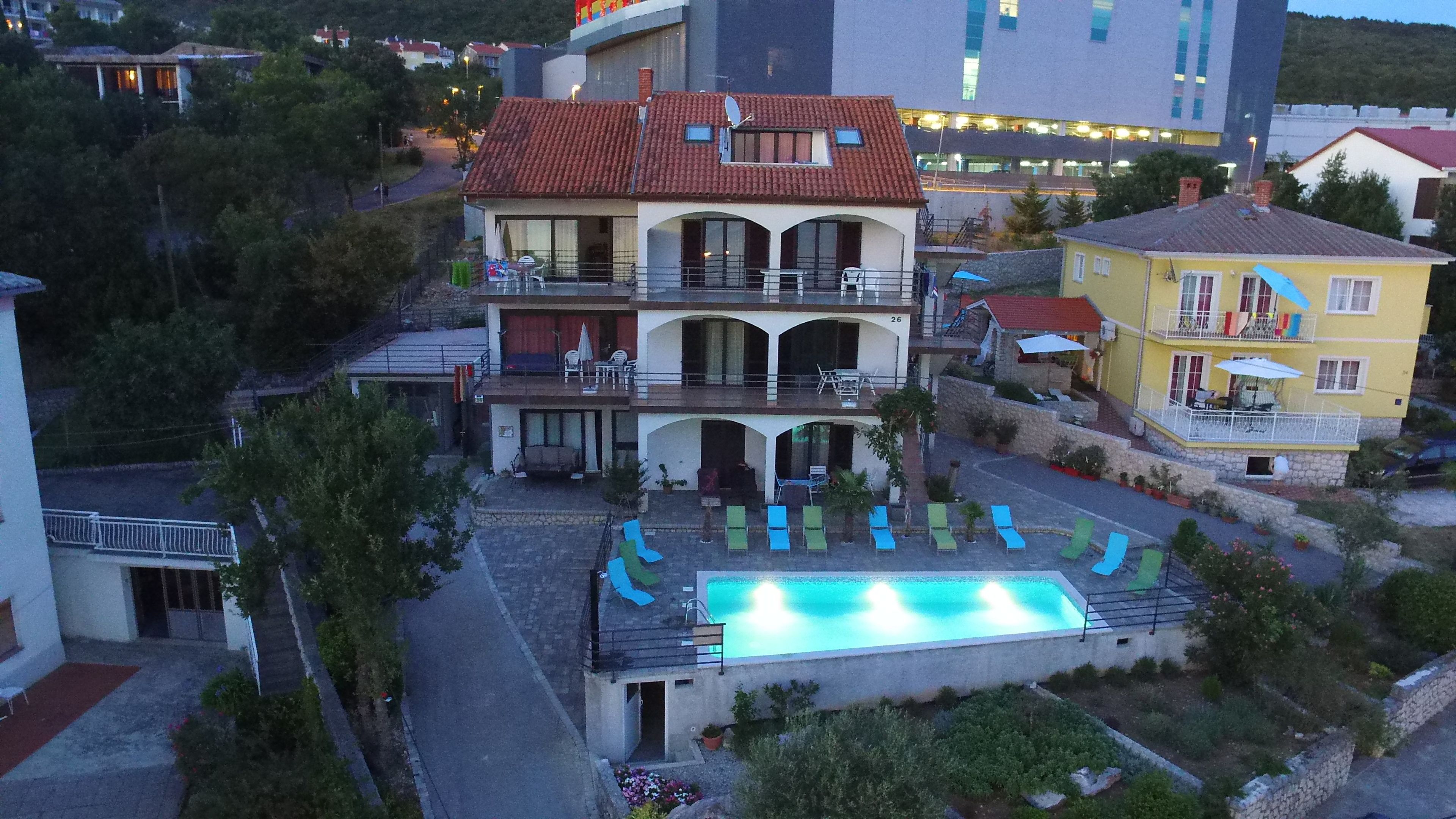 A two-story building with a swimming pool, outdoor seating, and a balcony.