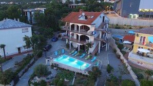 Ein mehrstöckiges Haus mit Swimmingpool, Sitzgelegenheit im Freien und einem Garten.