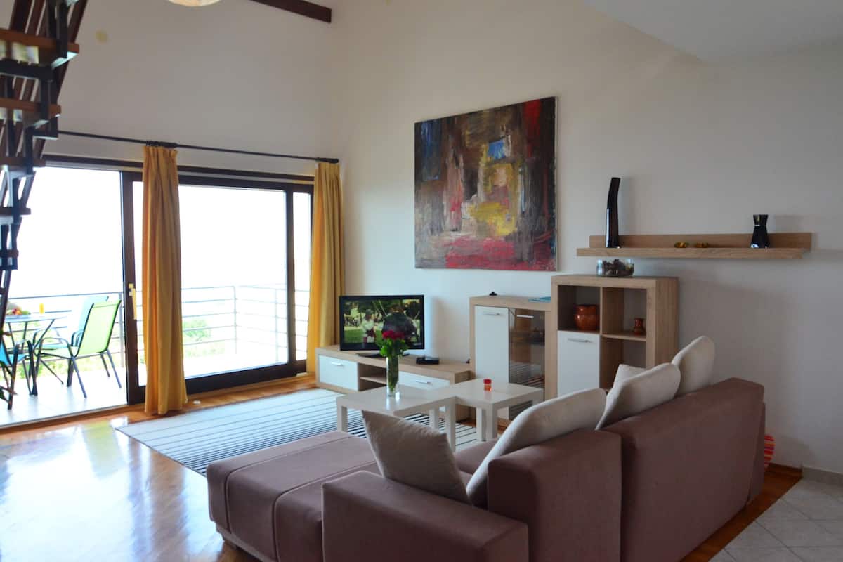 Una sala de estar moderna con un sofá, una mesa de centro, un televisor y un cuadro en la pared.