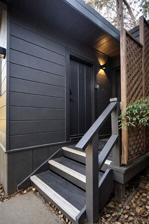 A building with a dark exterior, a wooden fence, and a staircase leading to a door. - Anderson Valley Inn (Philo)