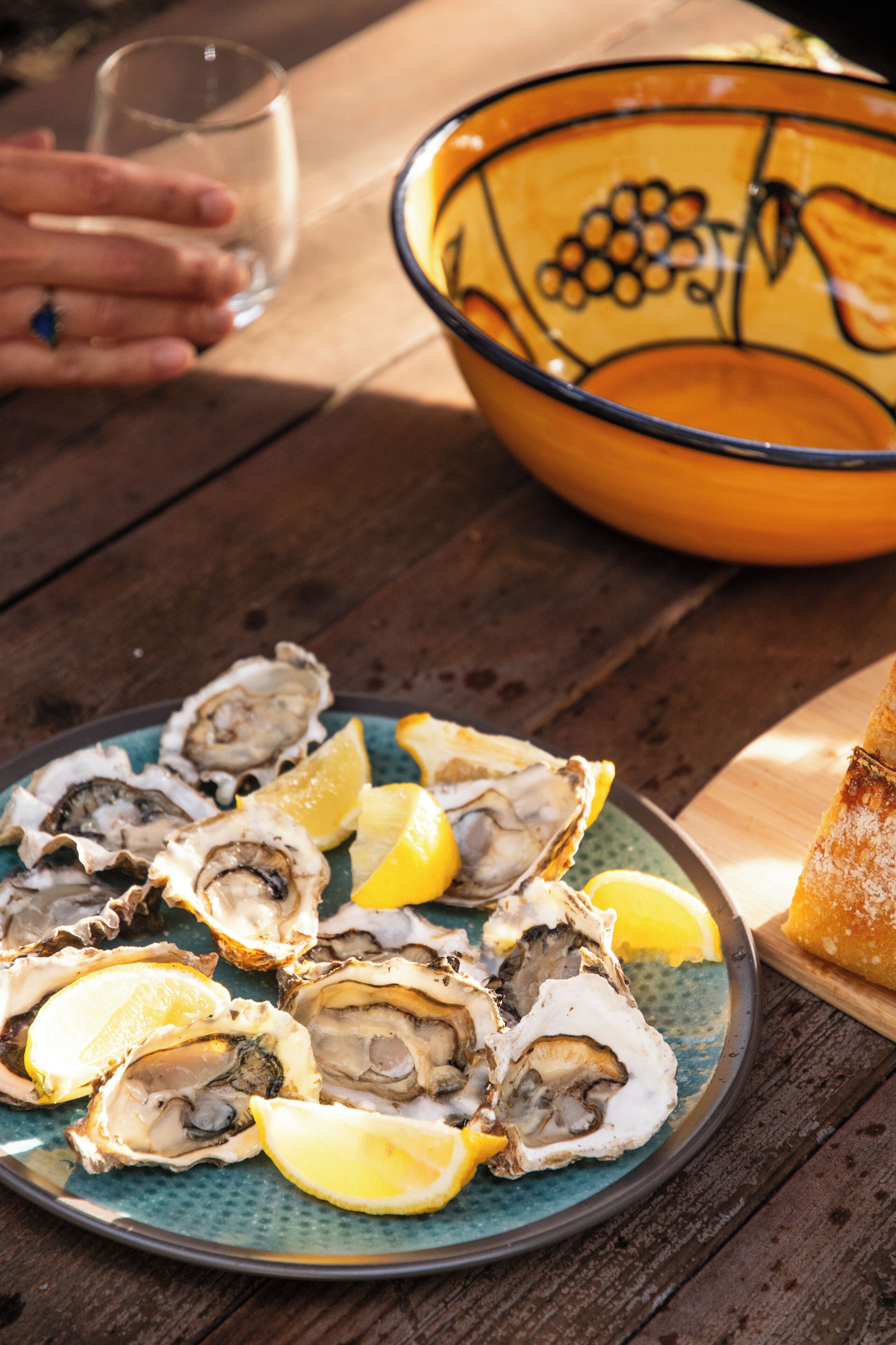 A plate of oysters with lemon wedges on a wooden table.