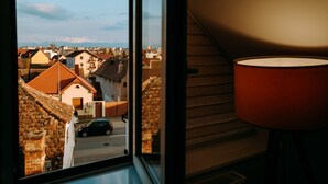 A room with a view of a street and buildings, a lamp, and a window. - Vila Anca (Sibiu)