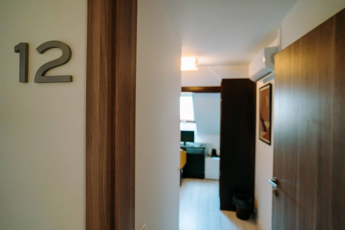 A hallway with a wooden door and a number '12' sign.