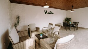 A modern interior with wicker furniture, a dining area, and a wall with "THE WANDA" text. - Vila Anca (Sibiu)