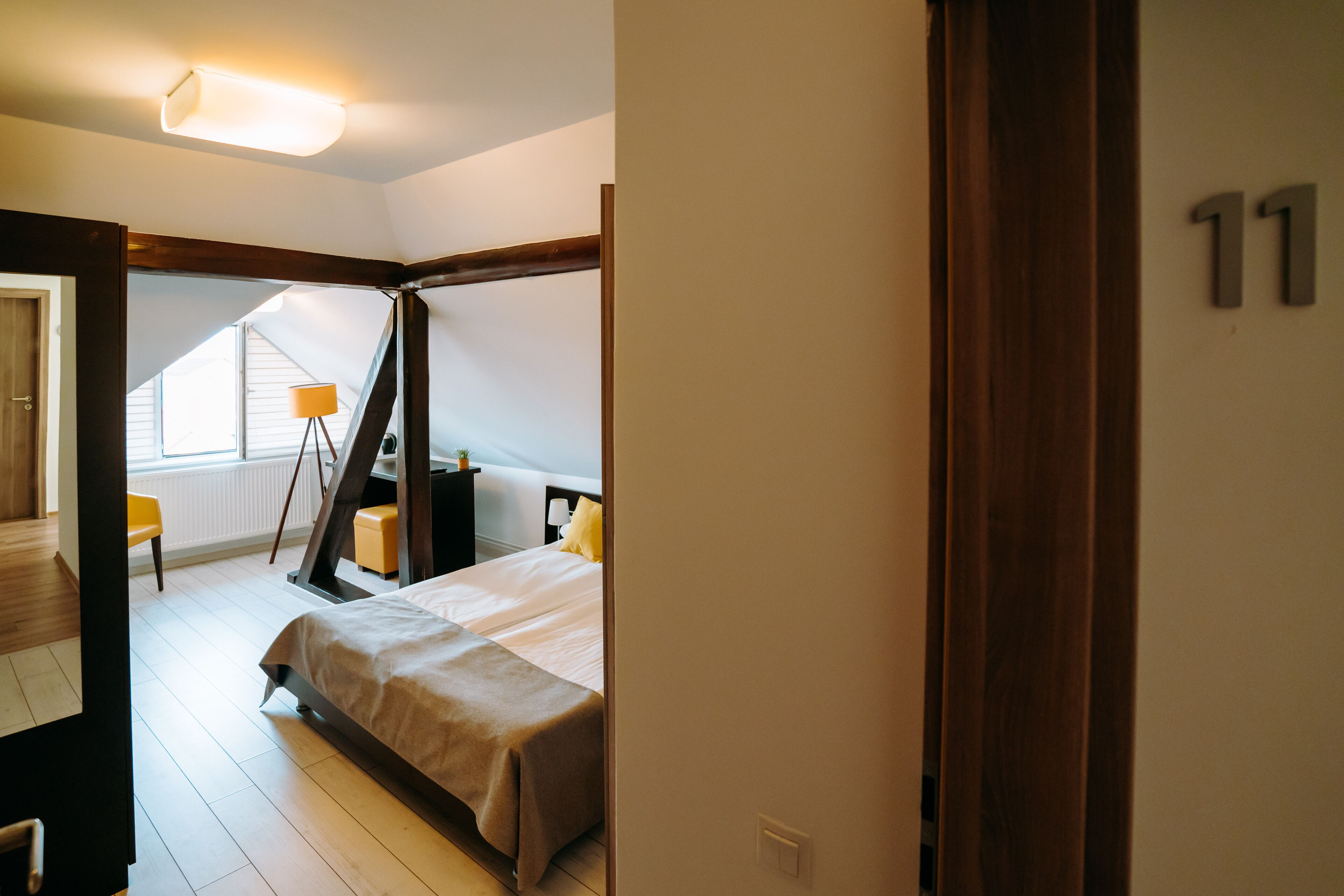 A bedroom with a bed, a bedside table, a lamp, and a window.