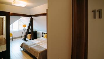 A bedroom with a bed, a bedside table, a lamp, and a window.