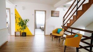 A modern interior with a wooden staircase, yellow and white walls, and a potted plant. - Vila Anca (Sibiu)