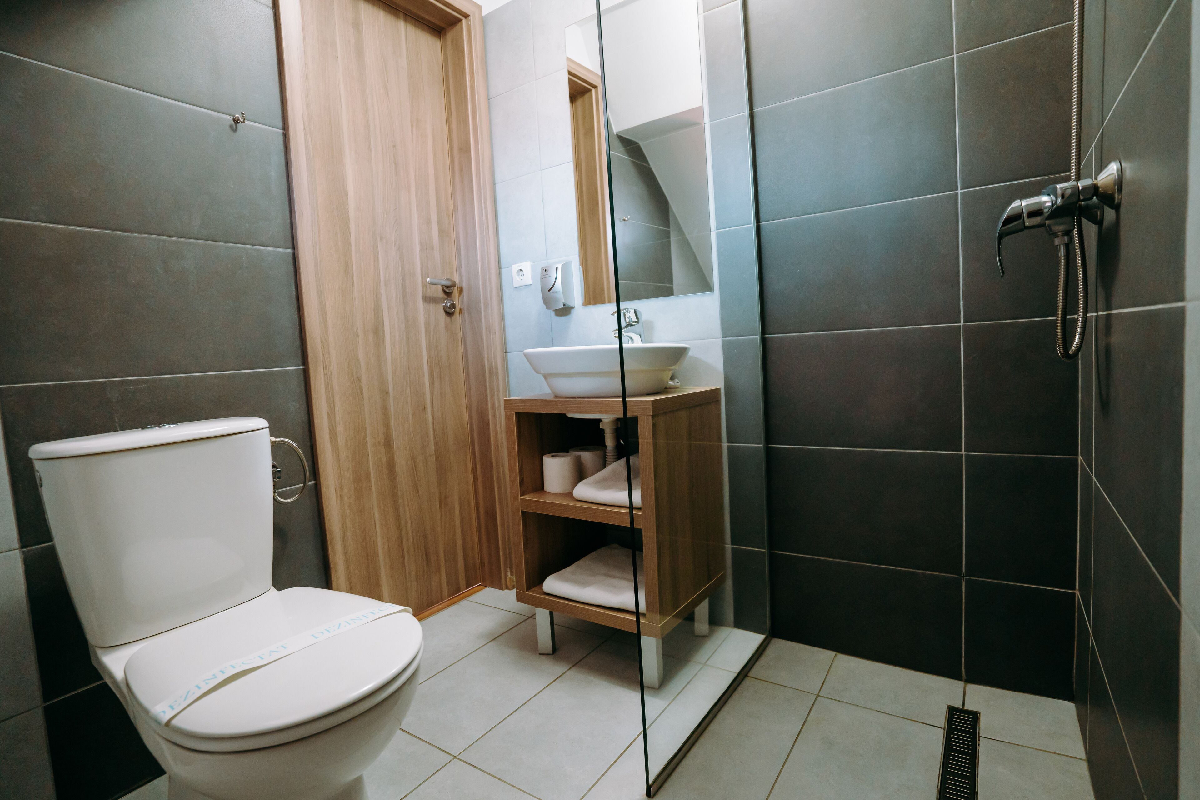 Uma casa de banho moderna com sanita, lavatório e chuveiro.