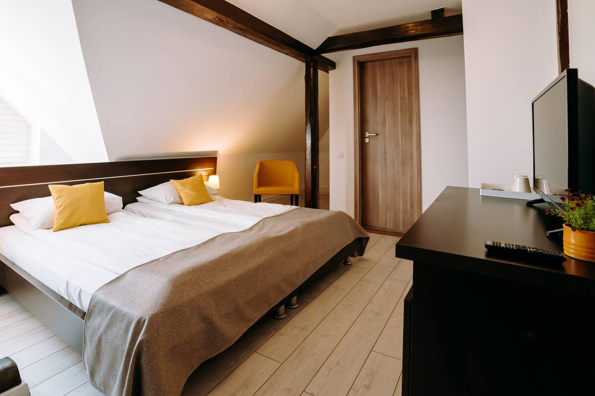A hotel room with a bed, a desk, a chair, and a door.