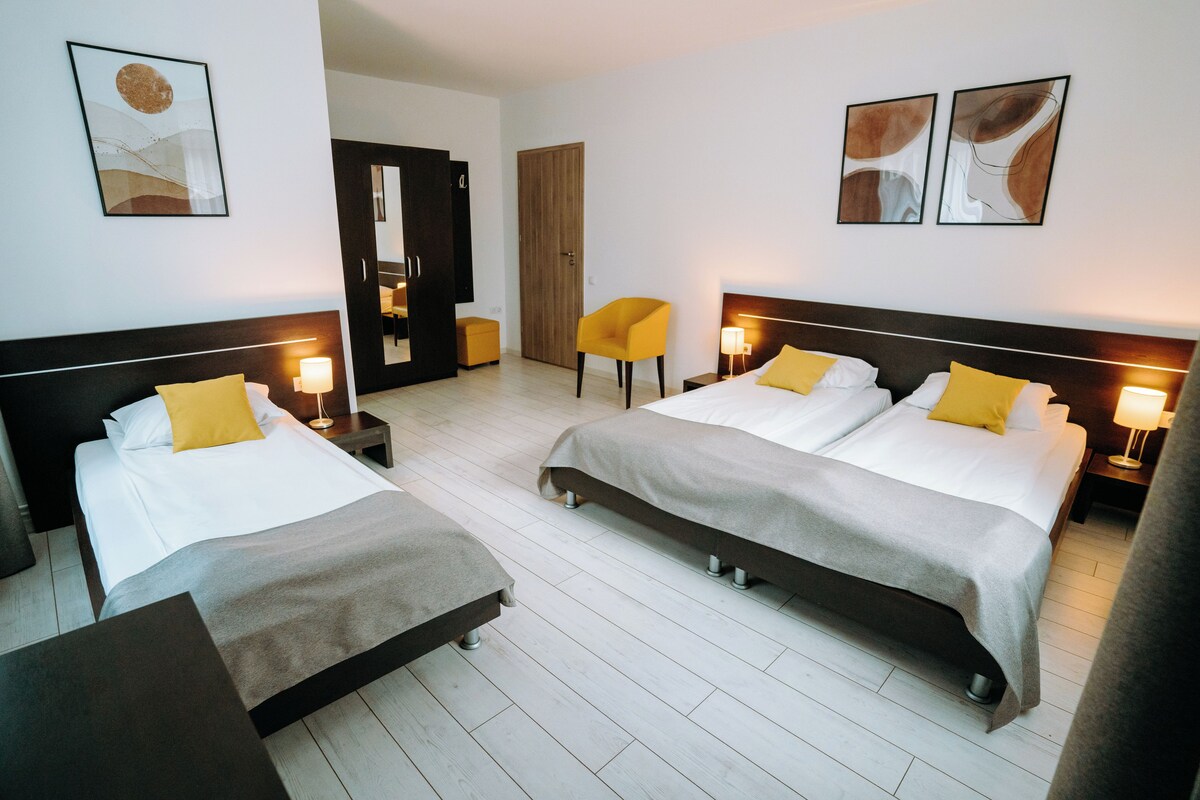 Habitación de hotel con dos camas, un armario de madera, una mesita y una silla.