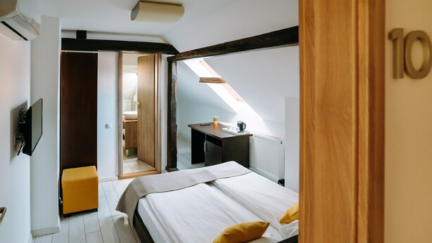 Un dormitorio con cama, una mesita, una planta y una ventana.