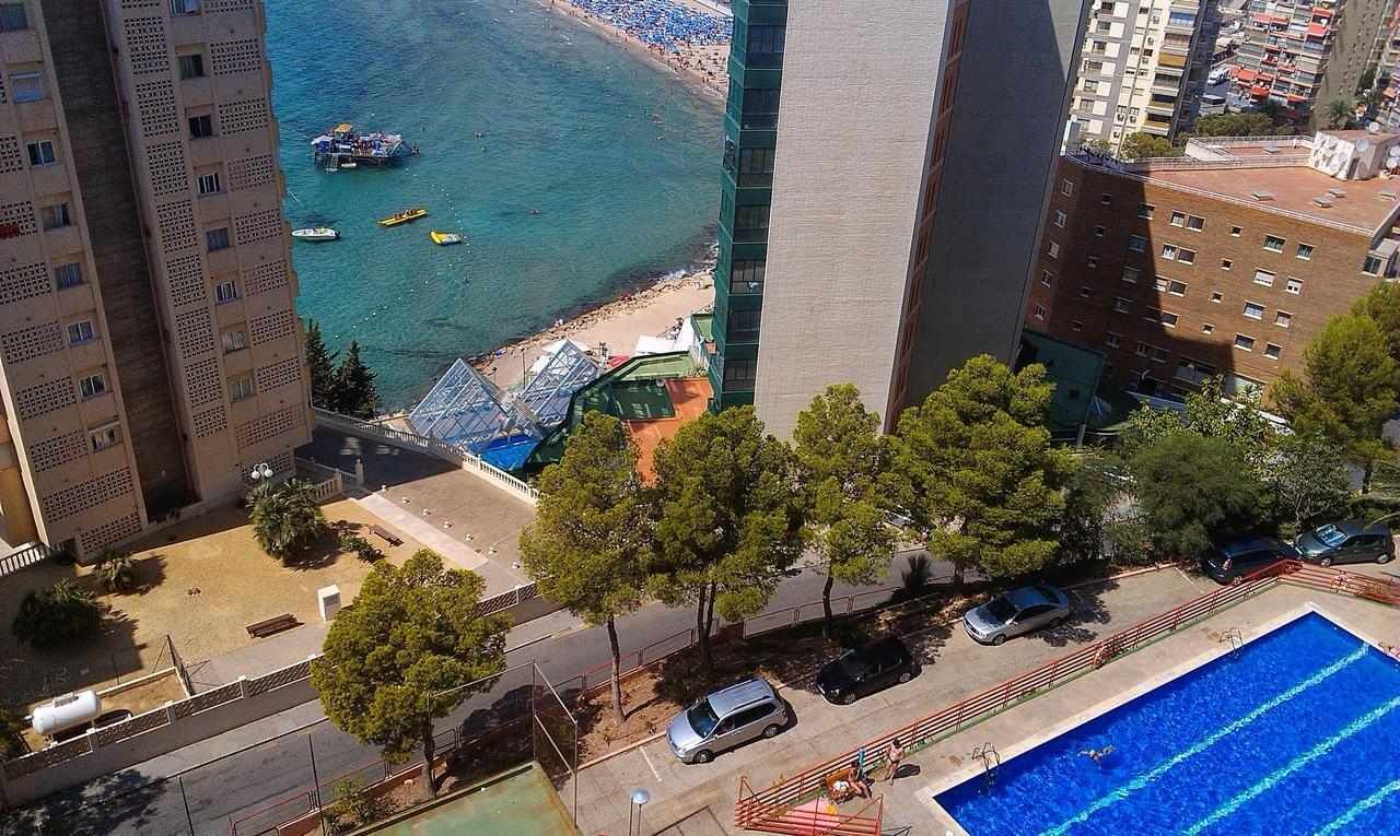Un edificio alto con piscina, playa y vista al mar.
