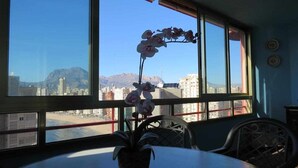 A room with a large window offering a view of a cityscape and mountains.