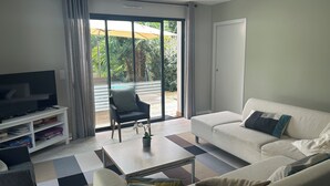 Ein Wohnzimmer mit Fernseher, Sofa, Sesseln und Couchtisch.