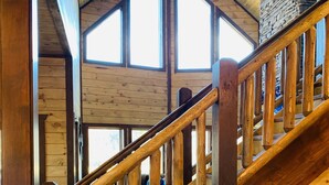 A wooden staircase with a stone wall and large windows.