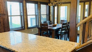 A kitchen with granite countertops, wooden cabinets, and a chandelier.