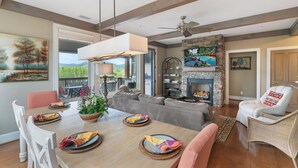 A spacious living room with a fireplace, a dining area with a table set for four, and a cozy seating area with a sofa and armchairs. - Chalakee Lodge CD-5- Mountain View, Gated Resort, Indoor/Outdoor Pools & Hot Tub (Boone)