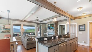 A spacious kitchen with a large island, a dining area with a view, and a cozy seating area with a fireplace. - Chalakee Lodge CD-5- Mountain View, Gated Resort, Indoor/Outdoor Pools & Hot Tub (Boone)