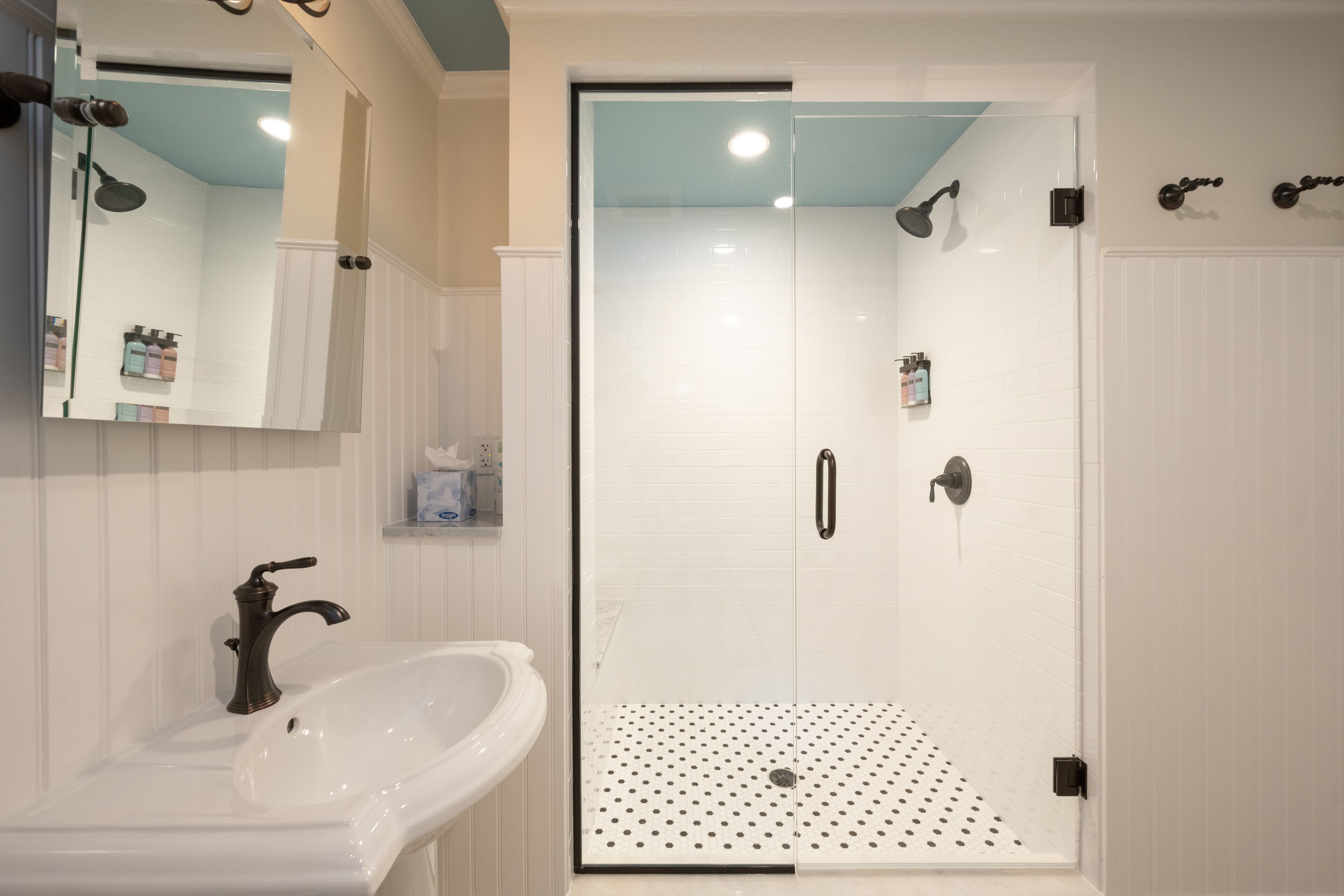 A bathroom with a white sink, a mirror, and a glass-enclosed shower area.