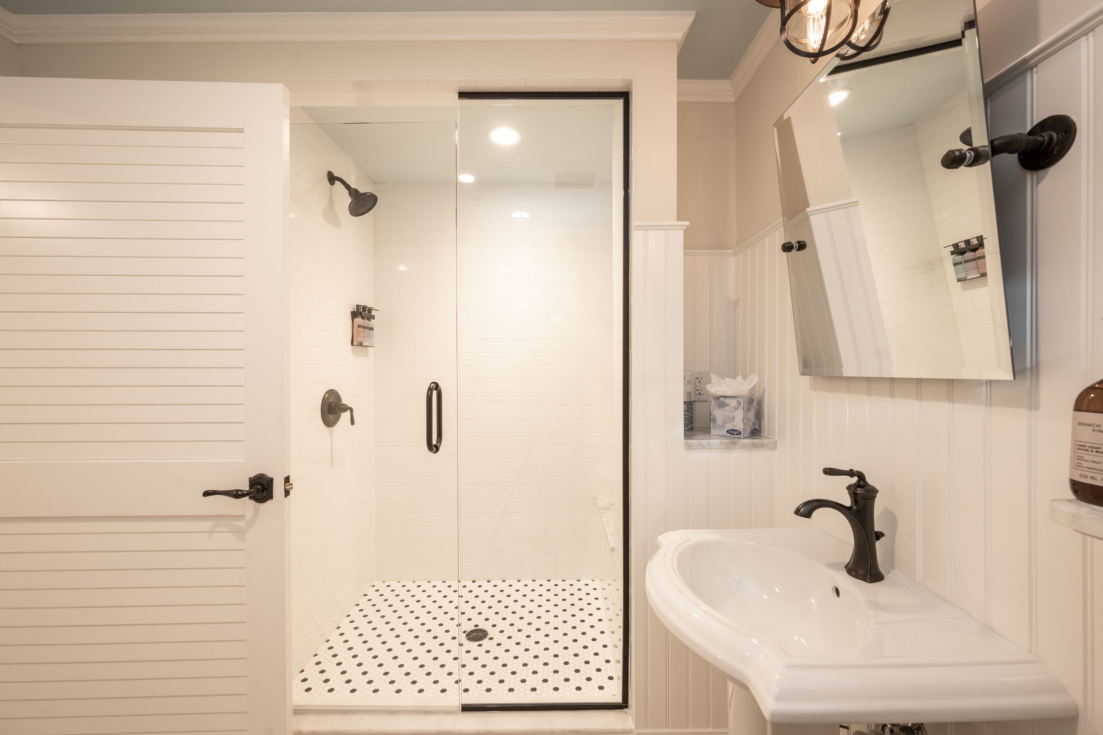 A bathroom with a shower, a sink, and a mirror.