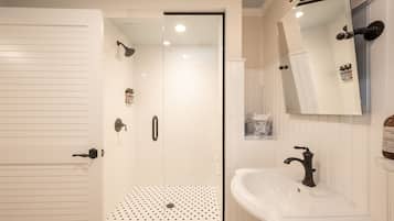 A bathroom with a shower, a sink, and a mirror.