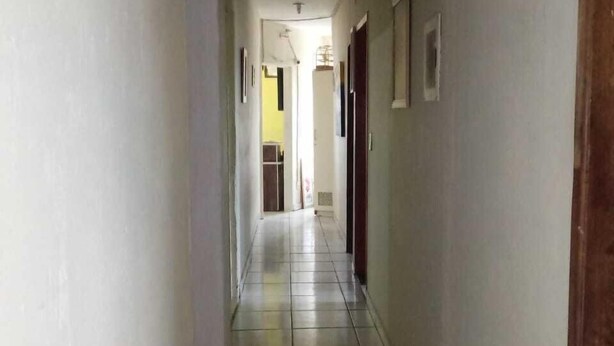Corredor estreito com placa indicando área acessível para cadeiras de rodas à esquerda.