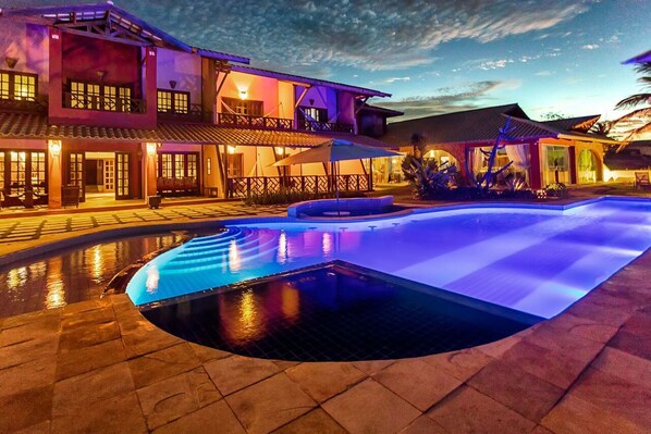 Un hotel con piscina, mobiliario exterior y una zona cubierta.