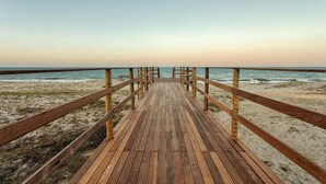 Une promenade en bois qui mène à la plage et offre une vue dégagée sur l’océan.