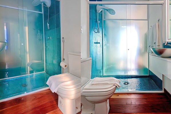 Un baño con ducha de vidrio, inodoro y lavamanos con espejo.