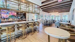 A spacious bar area with high stools, a television, and a variety of bottles and glasses on the counter.