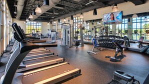 A gym with treadmills, weight machines, and dumbbells.
