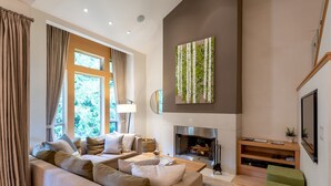 Ein modernes Wohnzimmer mit einer Couch, einem Kamin und einem großen Fenster.