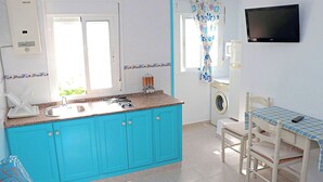 A compact kitchen with turquoise cabinets, a built-in sink, and a washing machine. - One bedroom apartment with WiFi (CONIL DE LA FRONTERA)