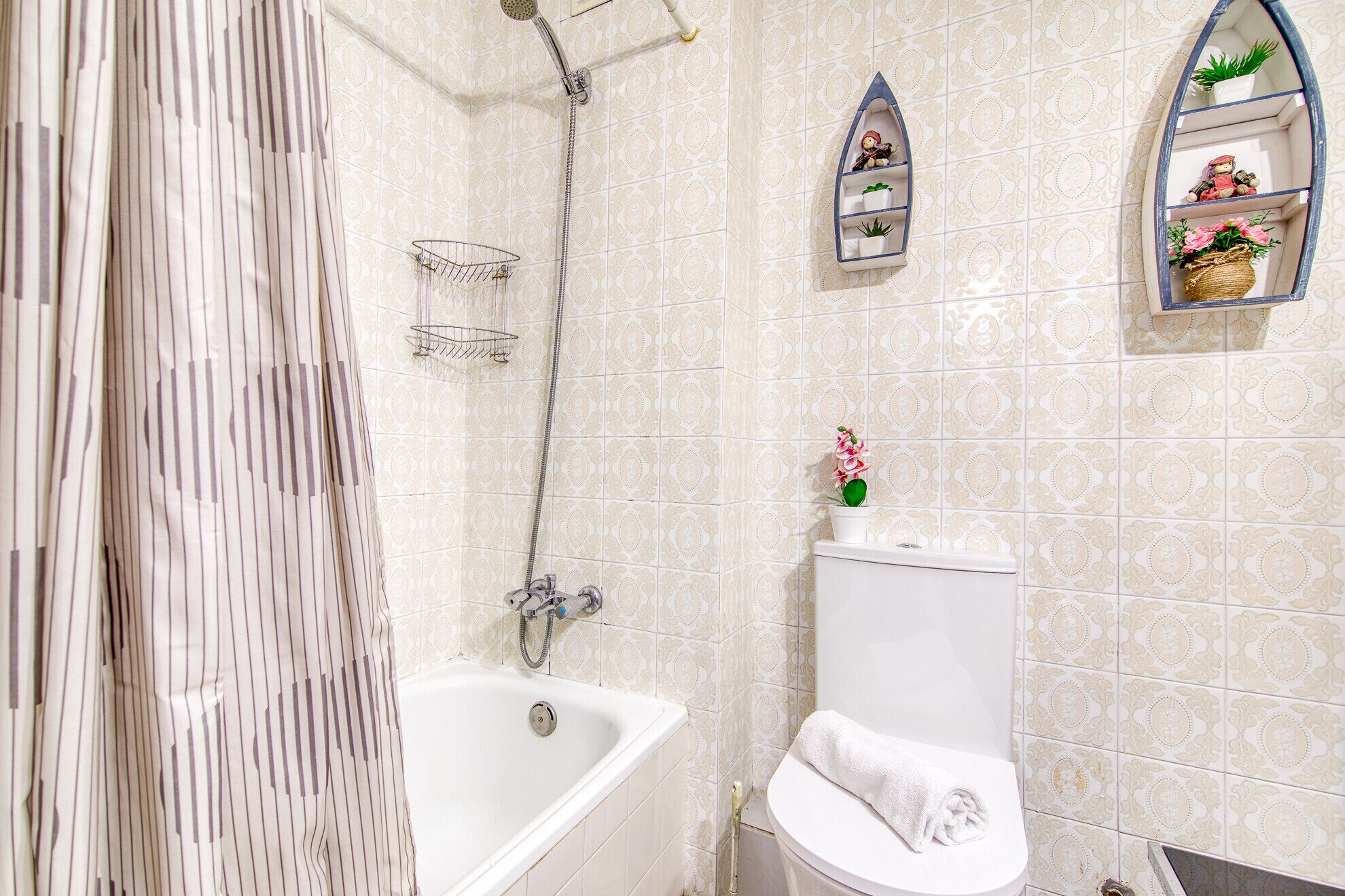 A bathroom with a bathtub, toilet, shower, and decorative shelves.