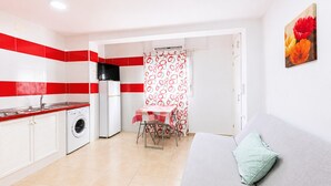 A compact living space with a kitchenette, a dining area, and a sofa.
