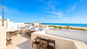 A rooftop terrace with outdoor seating and a view of the beach.