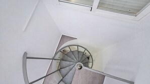 Una escalera en espiral con barandilla de metal y una persona de pie en la parte inferior.