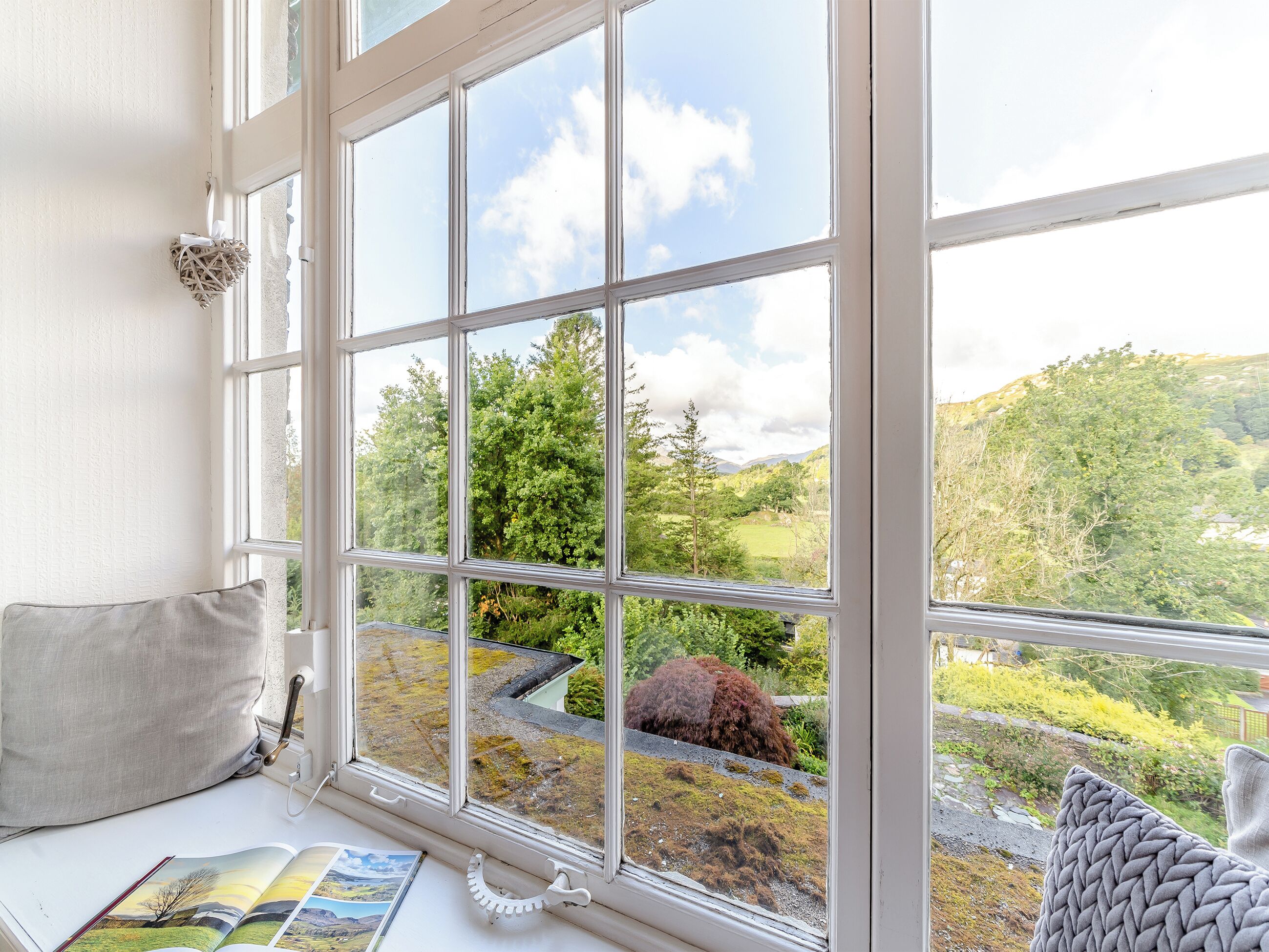 A room with a large window offering a view of a green landscape with trees and hills.