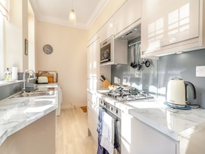 Una cocina moderna con un lavabo, estufa, horno y diversos utensilios.
