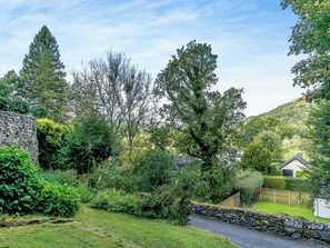 A stone wall, a grassy area, and a variety of trees.