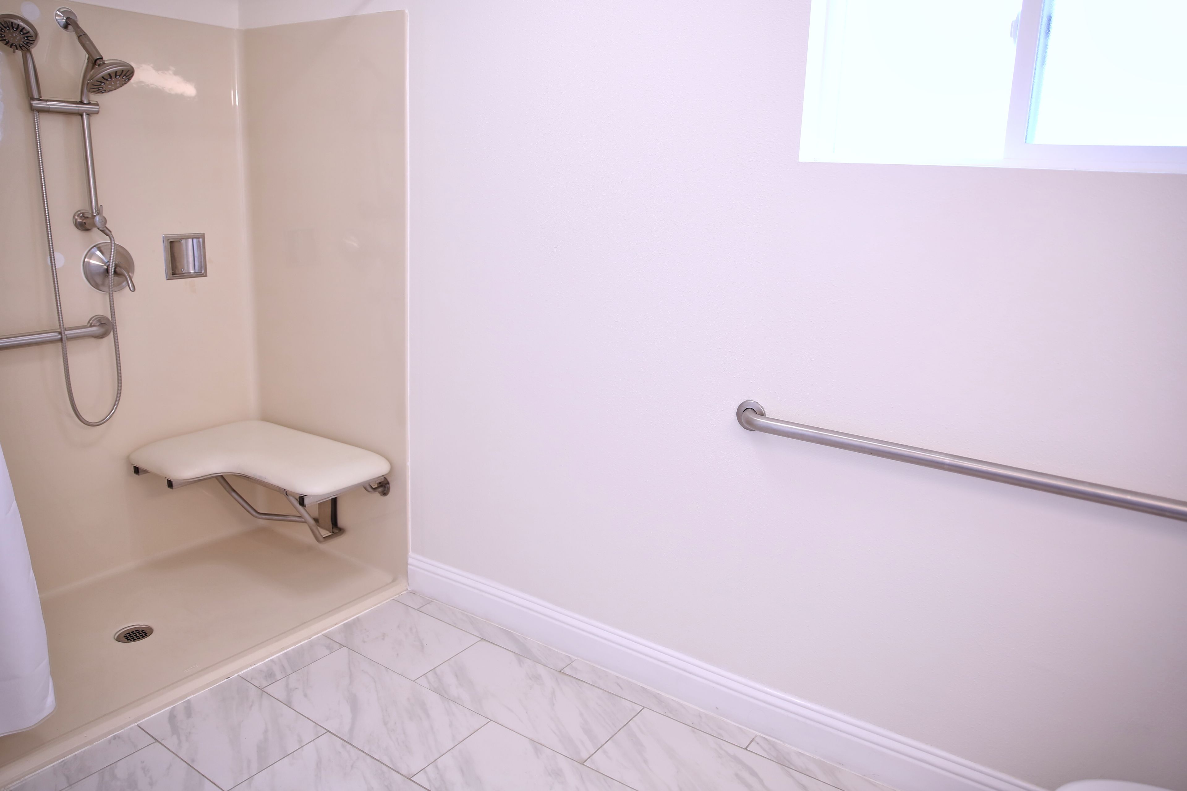 A bathroom with a shower, a grab bar, and a white toilet.